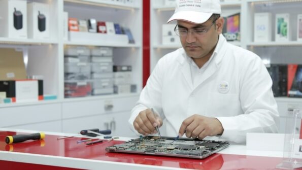 Technician performing MacBook repair London, working on a logic board inside a repair shop.